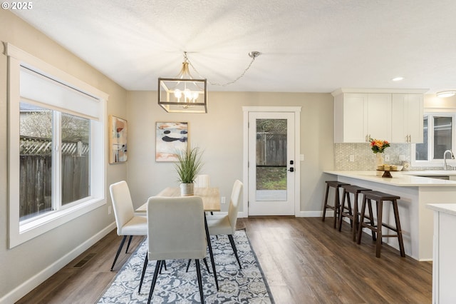 dining space featuring visible vents, baseboards, a notable chandelier, and dark wood finished floors