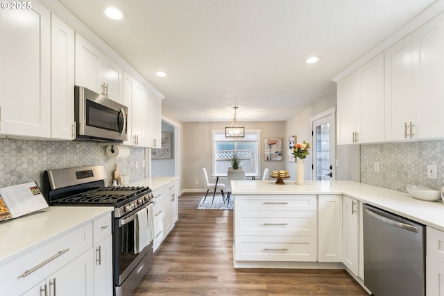 kitchen featuring dark wood-style floors, stainless steel appliances, a peninsula, white cabinets, and light countertops