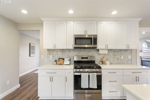 kitchen featuring dark wood-type flooring, tasteful backsplash, appliances with stainless steel finishes, white cabinets, and light countertops