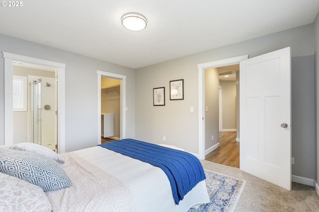 bedroom featuring visible vents, light carpet, a closet, baseboards, and a spacious closet