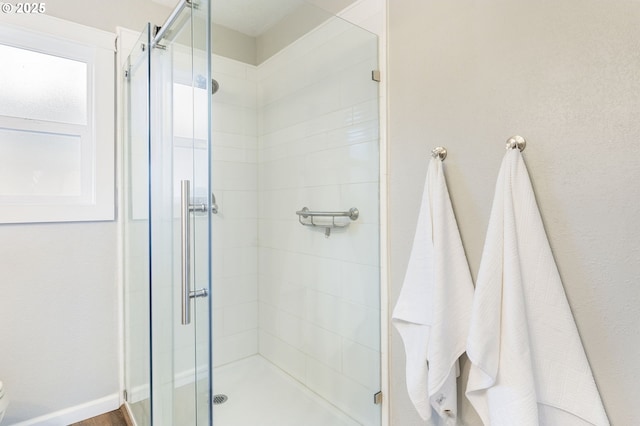 full bathroom featuring baseboards, toilet, and a shower stall