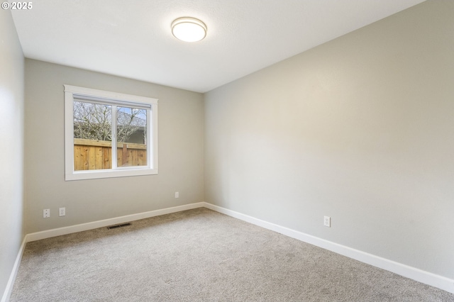 carpeted spare room featuring visible vents and baseboards