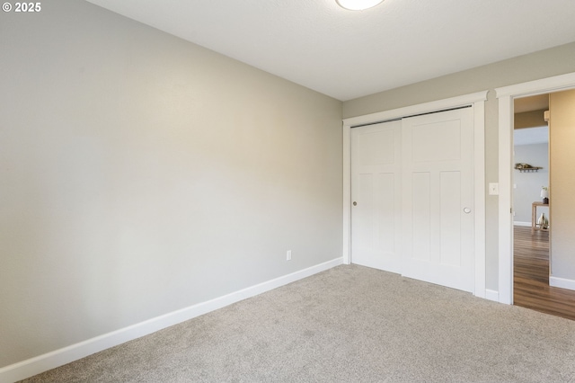 unfurnished bedroom with a closet, baseboards, and carpet flooring