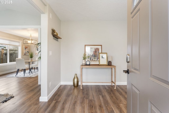 entrance foyer with an inviting chandelier, a textured ceiling, baseboards, and wood finished floors