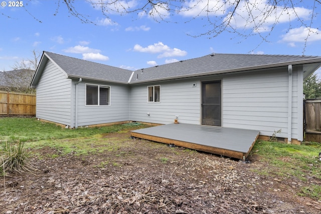 back of house with roof with shingles, a deck, and fence