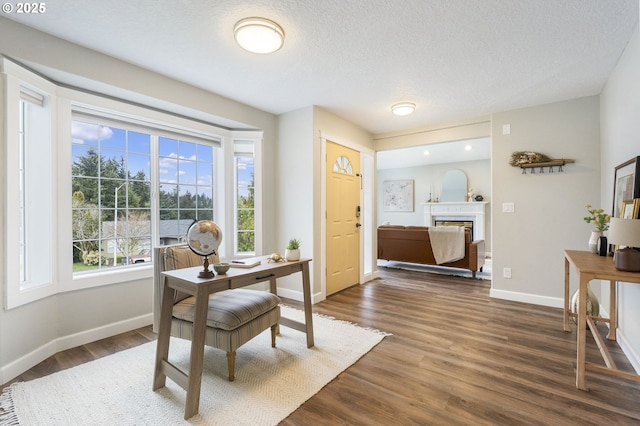 office area with baseboards, a textured ceiling, dark wood finished floors, and a fireplace