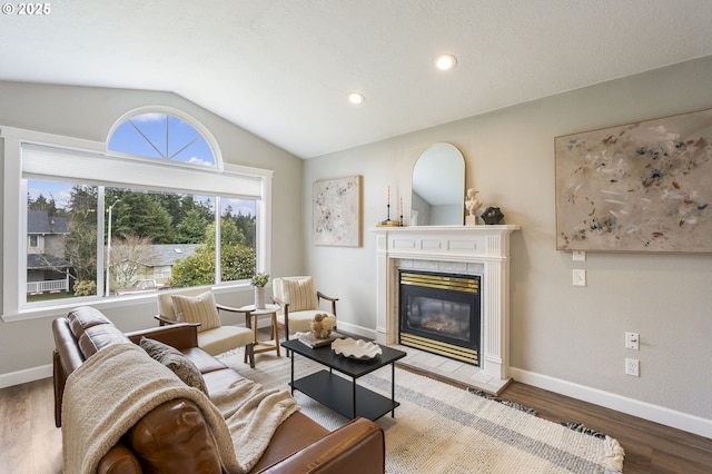 living area with wood finished floors, recessed lighting, baseboards, vaulted ceiling, and a tile fireplace