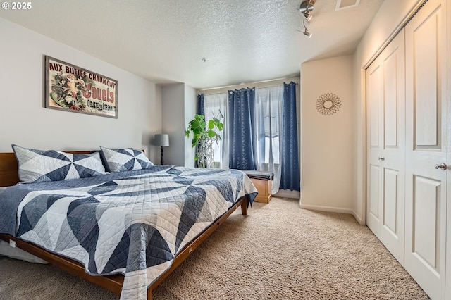 bedroom featuring baseboards, light carpet, a closet, and a textured ceiling