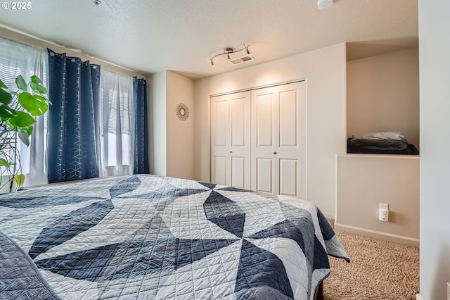 carpeted bedroom with a textured ceiling, a closet, baseboards, and visible vents