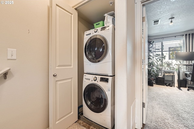 clothes washing area with stacked washer / dryer, a textured ceiling, carpet, visible vents, and laundry area