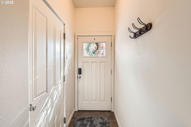 doorway to outside featuring dark tile patterned floors and baseboards