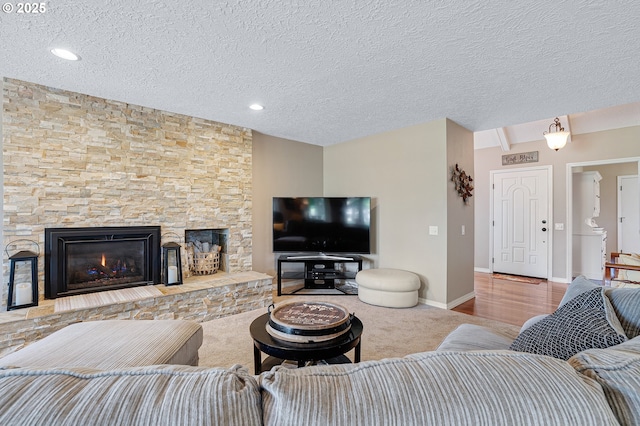 7250 SW Arbor Lake Dr, Wilsonville, OR 97070 - living room with a textured ceiling, a stone fireplace, baseboards, and recessed lighting