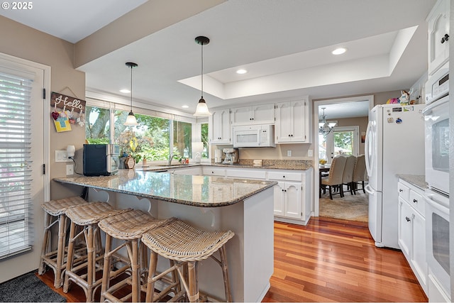 7250 SW Arbor Lake Dr, Wilsonville, OR 97070 - kitchen featuring white appliances, a peninsula, light wood-type flooring, a tray ceiling, and white cabinetry