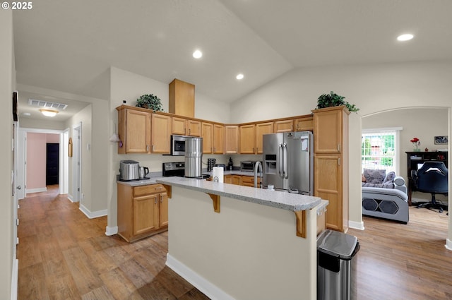 25246 Corky Ln, Veneta, OR 97487 - kitchen featuring appliances with stainless steel finishes, a breakfast bar, an island with sink, lofted ceiling, and light wood-type flooring