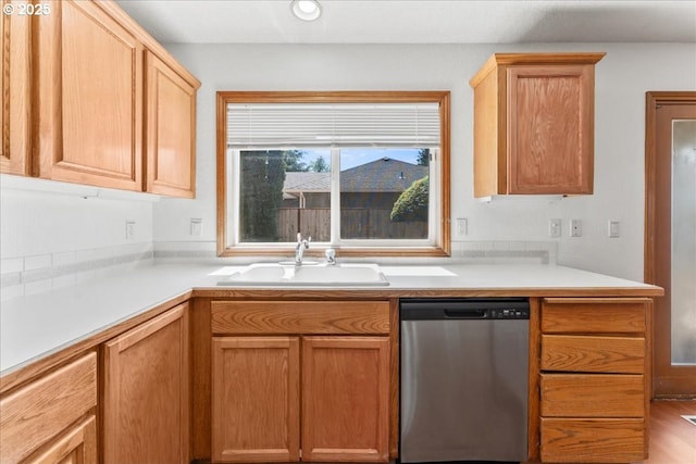 kitchen with stainless steel dishwasher, a sink, and light countertops