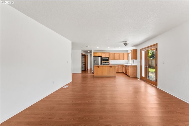 unfurnished living room with wood finished floors, baseboards, and a textured ceiling