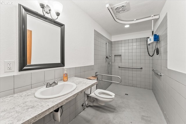 full bath featuring a sink, tile walls, a tile shower, and toilet