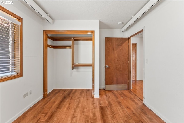 unfurnished bedroom with a closet, wood finished floors, and baseboards