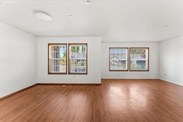 spare room featuring light wood-style flooring, healthy amount of natural light, and baseboards