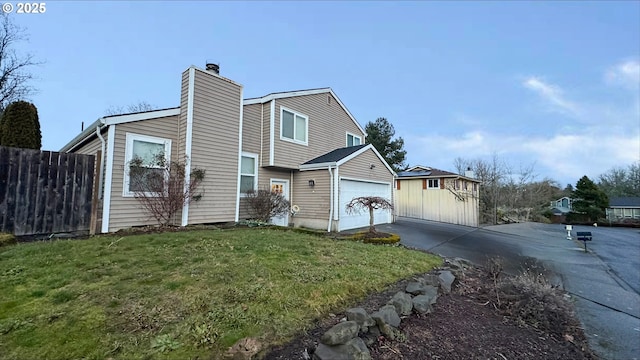 view of front facade featuring a garage, fence, driveway, a chimney, and a front yard