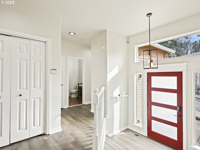 entryway featuring baseboards, visible vents, a chandelier, and wood finished floors