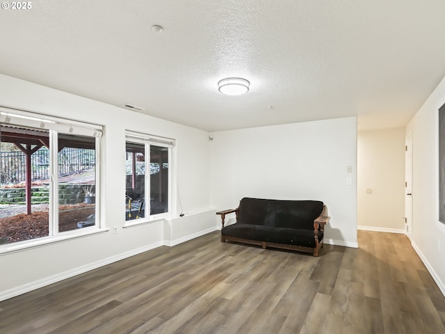 living area with a wealth of natural light, visible vents, baseboards, and wood finished floors