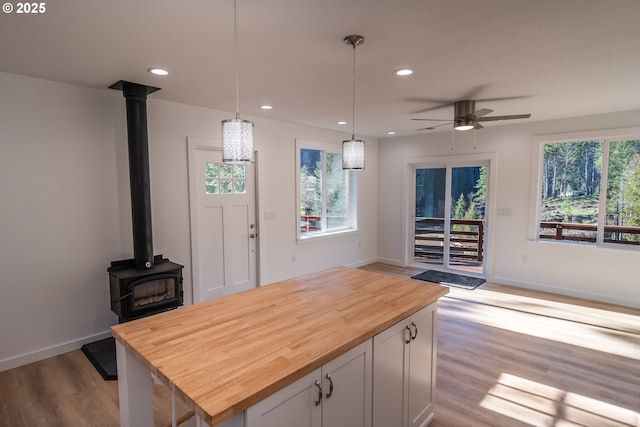 kitchen featuring recessed lighting, butcher block counters, a wood stove, and wood finished floors