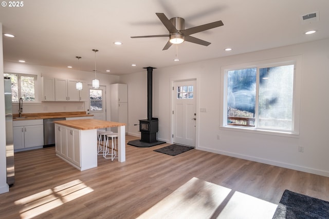 kitchen featuring a breakfast bar area, light wood-style flooring, a sink, wood counters, and stainless steel dishwasher