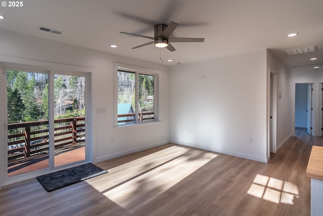 empty room with wood finished floors, visible vents, and recessed lighting