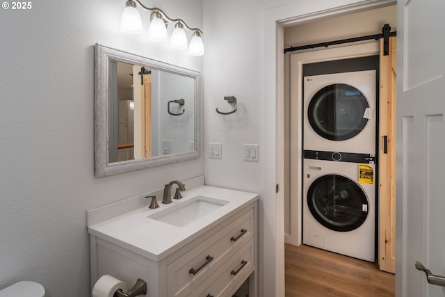 bathroom with wood finished floors, vanity, and stacked washer / drying machine