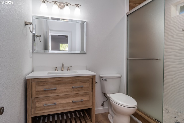 bathroom with toilet, a shower stall, wood finished floors, and vanity