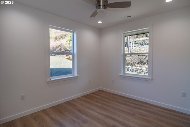 spare room with visible vents, wood finished floors, a wealth of natural light, and baseboards