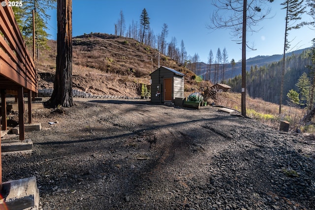 view of gate featuring an outbuilding, a mountain view, and a storage unit