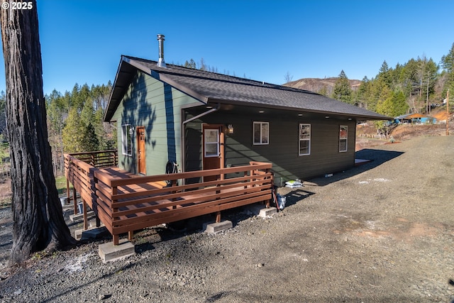 back of property featuring a deck and a shingled roof