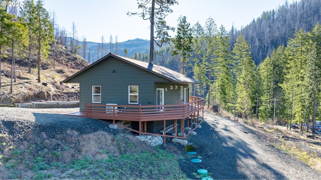 exterior space featuring a deck with mountain view and a forest view