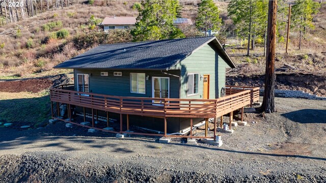 view of front facade with a shingled roof and a wooden deck