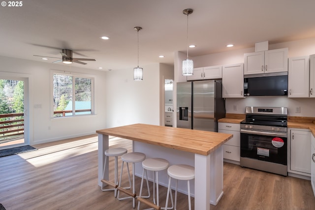 kitchen with recessed lighting, wooden counters, appliances with stainless steel finishes, light wood-type flooring, and a kitchen breakfast bar