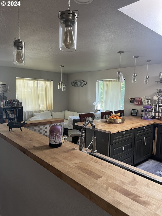 62760 Koski Rd, Coos Bay, OR 97420 - kitchen featuring butcher block counters, open floor plan, dark cabinets, a textured ceiling, and hanging light fixtures