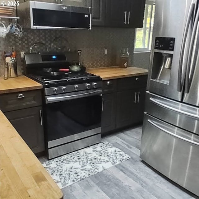 62760 Koski Rd, Coos Bay, OR 97420 - kitchen featuring wooden counters, stainless steel appliances, tasteful backsplash, light wood finished floors, and dark cabinetry