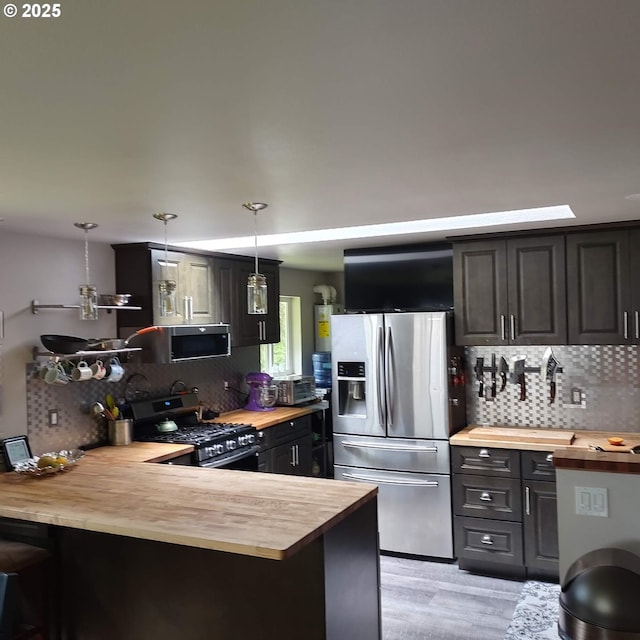 62760 Koski Rd, Coos Bay, OR 97420 - kitchen featuring wood counters, appliances with stainless steel finishes, tasteful backsplash, and a peninsula