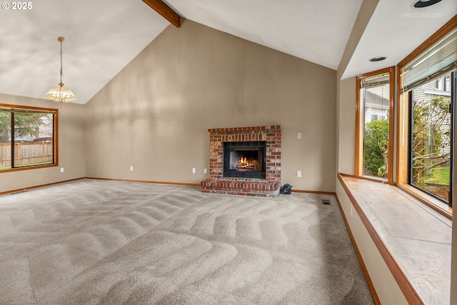 unfurnished living room featuring a brick fireplace, lofted ceiling with beams, a wealth of natural light, and carpet floors