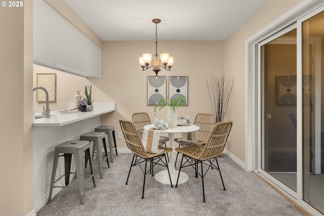 dining room featuring sink, light carpet, and a chandelier