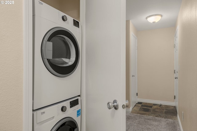 laundry room with stacked washer / drying machine and dark colored carpet