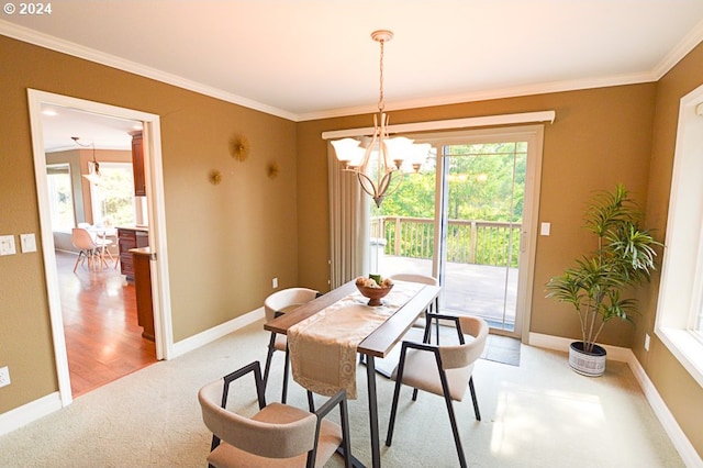 carpeted dining room featuring ornamental molding and an inviting chandelier