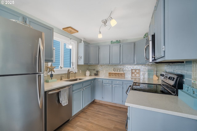 kitchen featuring decorative light fixtures, stainless steel appliances, tasteful backsplash, sink, and light hardwood / wood-style flooring