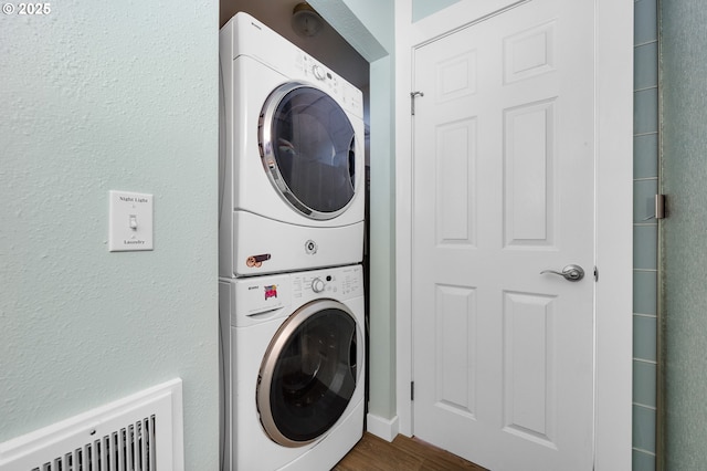 laundry area with stacked washer and clothes dryer and dark hardwood / wood-style flooring