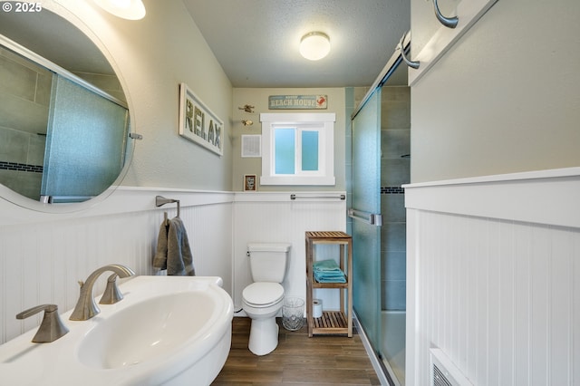 bathroom with toilet, a textured ceiling, hardwood / wood-style flooring, sink, and a shower with door