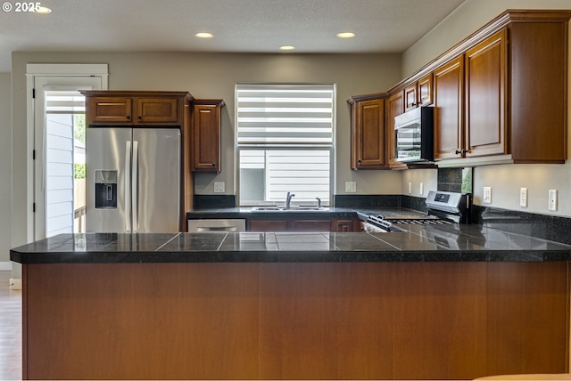 2514 NW Parnell Ter, Portland, OR 97229 - kitchen with stainless steel appliances, a peninsula, tile counters, and recessed lighting