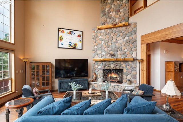 living room with a towering ceiling, wood-type flooring, and a fireplace