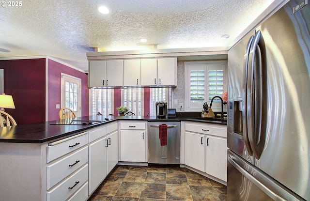 10535 SW 135th Ave, Beaverton, OR 97008 - kitchen with stainless steel appliances, a peninsula, plenty of natural light, a textured ceiling, and stone finish flooring